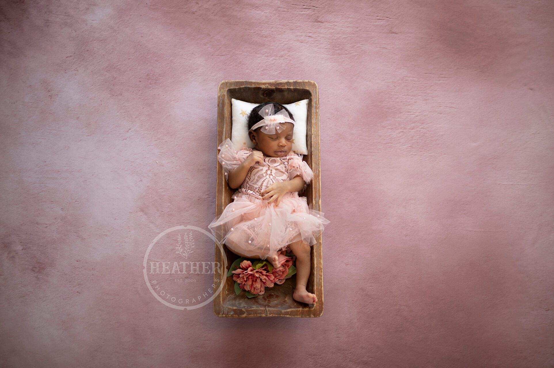 A soft pink backdrop adds a touch of sweetness and innocence, ideal for capturing baby girl portraits