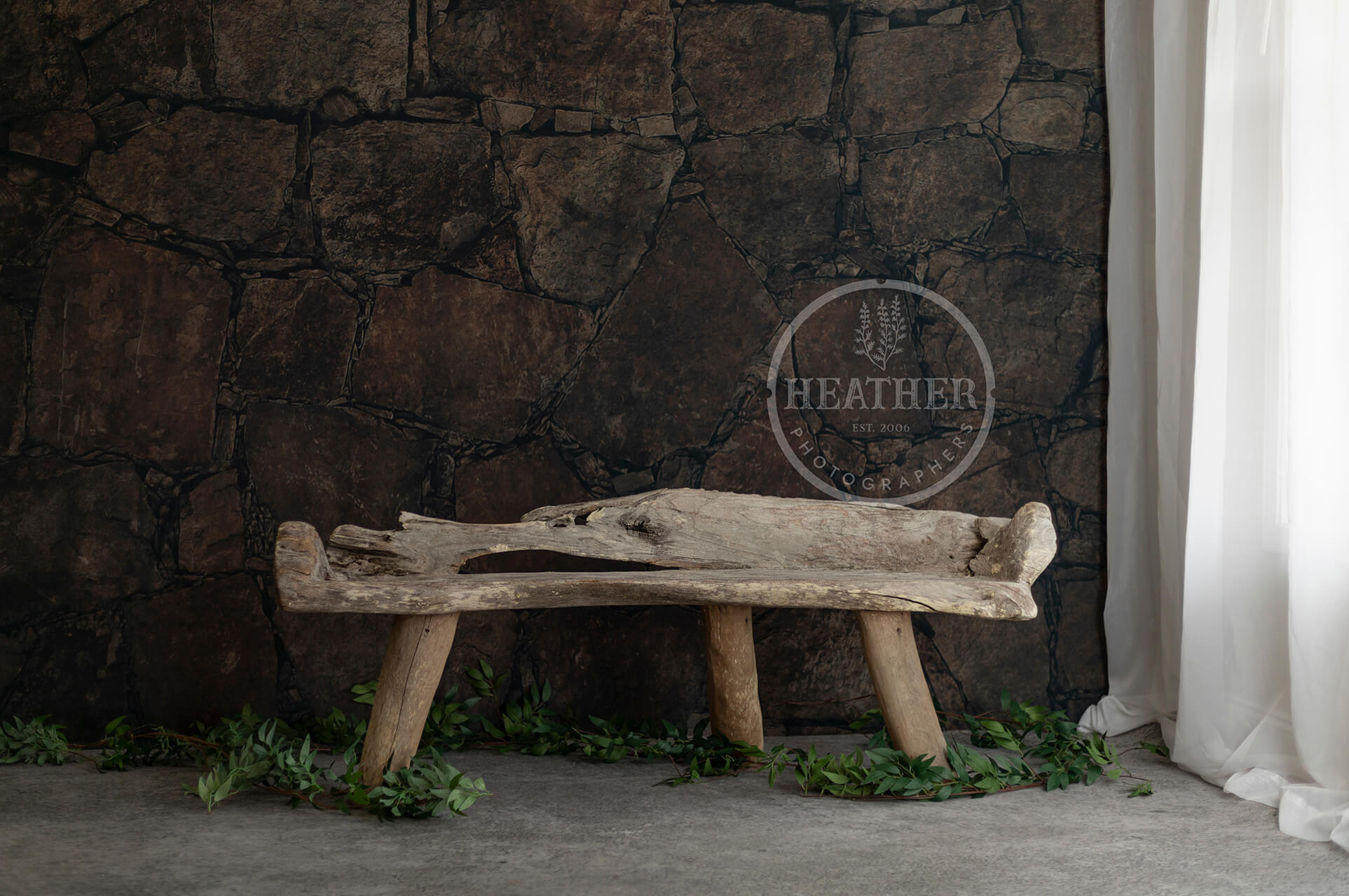 bench made with river wood on old stone wall backdrop