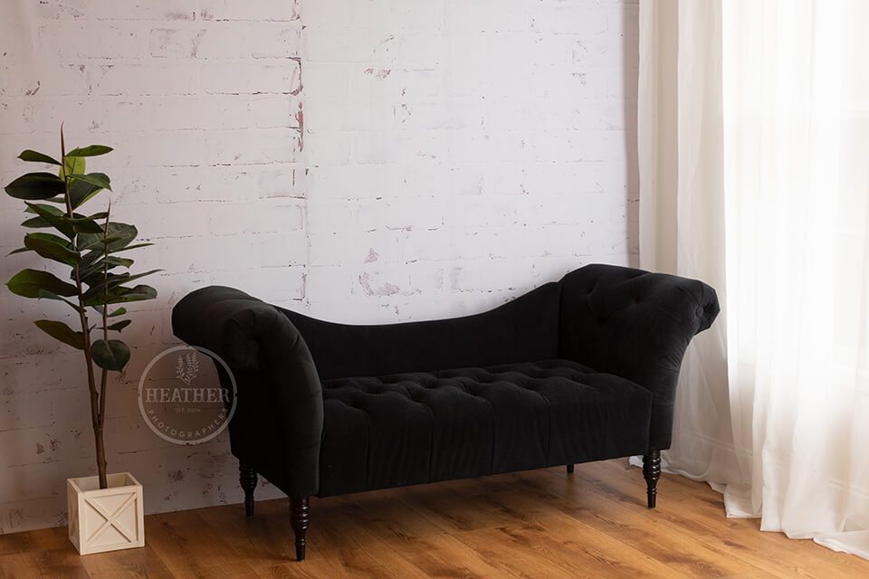 elegant black sofa against limewash brick